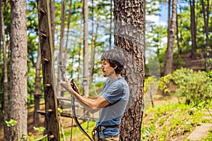 Young attractive man in adventure rope park in safety equipment