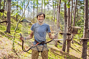 Young attractive man in adventure rope park in safety equipment