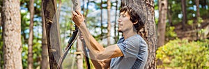 Young attractive man in adventure rope park in safety equipment BANNER, LONG FORMAT
