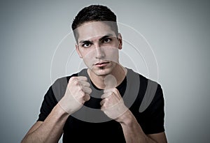 Young attractive man with an angry face in boxing stance ready to fight