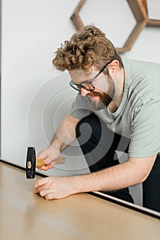 Young attractive man assembles furniture - handwerker and interior objects concept