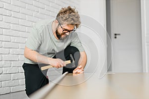 Young attractive man assembles furniture - handwerker and interior objects concept