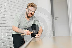 Young attractive man assembles furniture - handwerker and interior objects concept