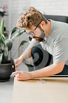 Young attractive man assembles furniture - handwerker and interior objects concept