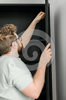 Young attractive man assembles furniture - handwerker and interior objects concept