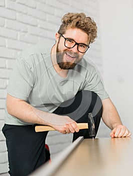 Young attractive man assembles furniture - handwerker and interior objects concept