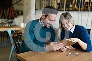 Young attractive man and beautiful woman on date looking on tablet