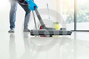 Young attractive man is cleaning vacuum commercial cleaning equipment on floor at home helping wife.