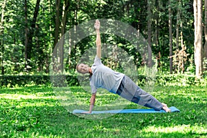 Young attractive man doing yoga in the park: posture  plank.