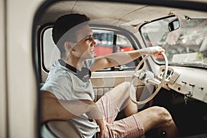 A young and attractive man is driving a vintage car