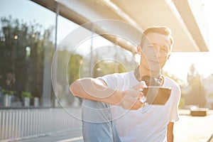 Young attractive man enjoying a cup of aromatic coffee outdoors in sunny weather