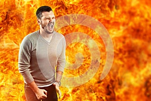A young attractive man feels pain in a flame, surrounded by hot fire. He feels hate, anger, anger, envy photo