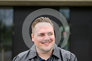 Young man in a black leather jacket and slicked back hair looking friendly to the side photo