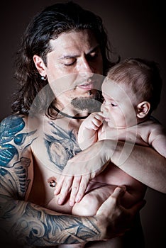 Young attractive man holding a newborn baby studio shot