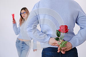 Young attractive man holding a rose behind his back to surprise his lover.