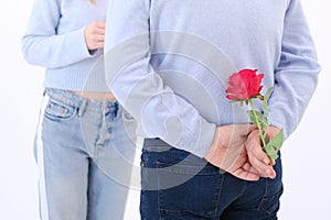 Young attractive man holding a rose behind his back to surprise his lover.