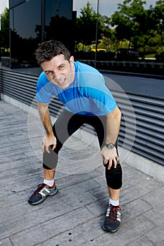 Young attractive man leaning exhausted after running session sweating taking a break to recover in urban street photo