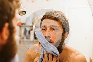 Young attractive man looking in mirror in morning