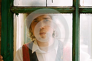 Young attractive man looking through a window's glass.