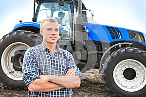 Young attractive man near a tractor. Concept of agriculture.