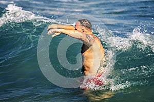 Young and attractive man with raised up hands trying to dive into the water.