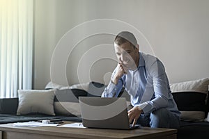 09.06.2022 - Pleven,Bulgaria - Young attractive man sitting on sofa at home working on laptop online, using internet, smiling,