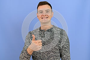 Young attractive man smiles at the camera and shows a thumb up