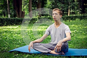 Young attractive man in sport clothes is meditating in the lotus position with a pacified face photo