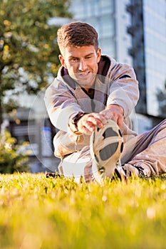 Young attractive man stretching his legs in park