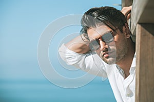 Joven atractivo hombre gafas de sol buscando afuera a través de el mar durante verano 