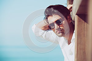 Young attractive man with sunglasses looking out over the sea during the summer.