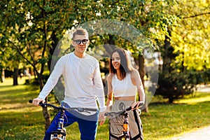 Young attractive man in sunglasses and smiling woman are looking at the camera, posing for the photo with their sport bikes, city