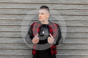 Young attractive man in trendy black and red checkered jacket in a trendy black t-shirt with amulet posing