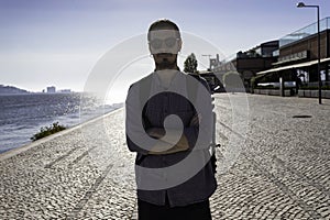 A young attractive man walking along the riverside of Tejo river in the city of Lisbon in Portugal. The April 25th bridge in the photo