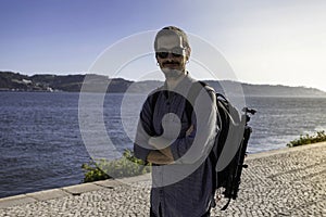 A young attractive man walking along the riverside of Tejo river in the city of Lisbon in Portugal. The April 25th bridge in the photo