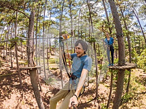 Young attractive man and woman in adventure rope park in safety equipment