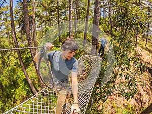 Young attractive man and woman in adventure rope park in safety equipment