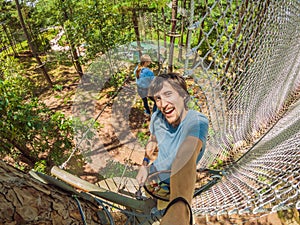 Young attractive man and woman in adventure rope park in safety equipment