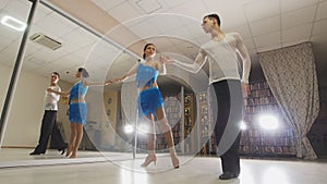 Young attractive man and woman dancing Latin American dance in costumes in the Studio, slow motion, close up, in action