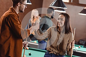 young attractive man and woman holding hands in pool bar