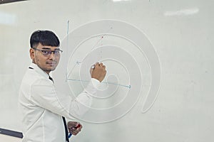 Young attractive man is writing a business plan on whiteboard.