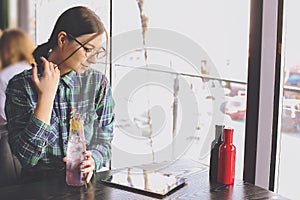 Happy young woman drinking cappuccino, latte, macchiato, tea, using tablet computer and talking on the phone in a coffee shop / ba