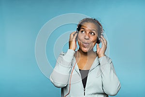 Young attractive mixed race woman enjoying music listening with headphones blue background