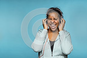 Young attractive mixed race woman enjoying music listening with headphones blue background