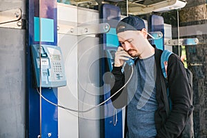 Young attractive modern man talking on the payphone