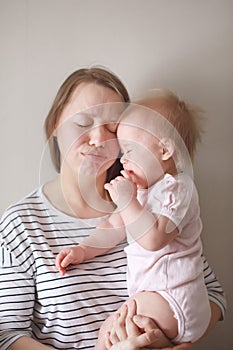 Young attractive mother holding her little crying baby on her hands