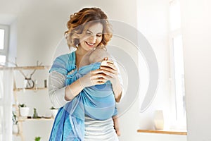 Young attractive mother smiles and looking through photos of son on cell phone trying send some pics to her husband