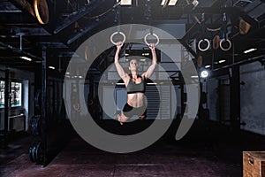 Young attractive muscular strong fit girl swinging on gymnastic ring heavy hardcore cross workout swing workout training in the gy