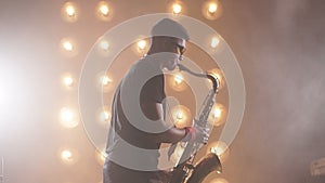 Young attractive musician plays tenor saxophone on stage