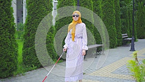 Young attractive muslim woman visually impaired with a walking cane in the park